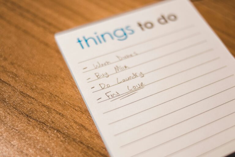 to-do list on wooden table with items like dishes, laundry, and "find love" (double underline)
